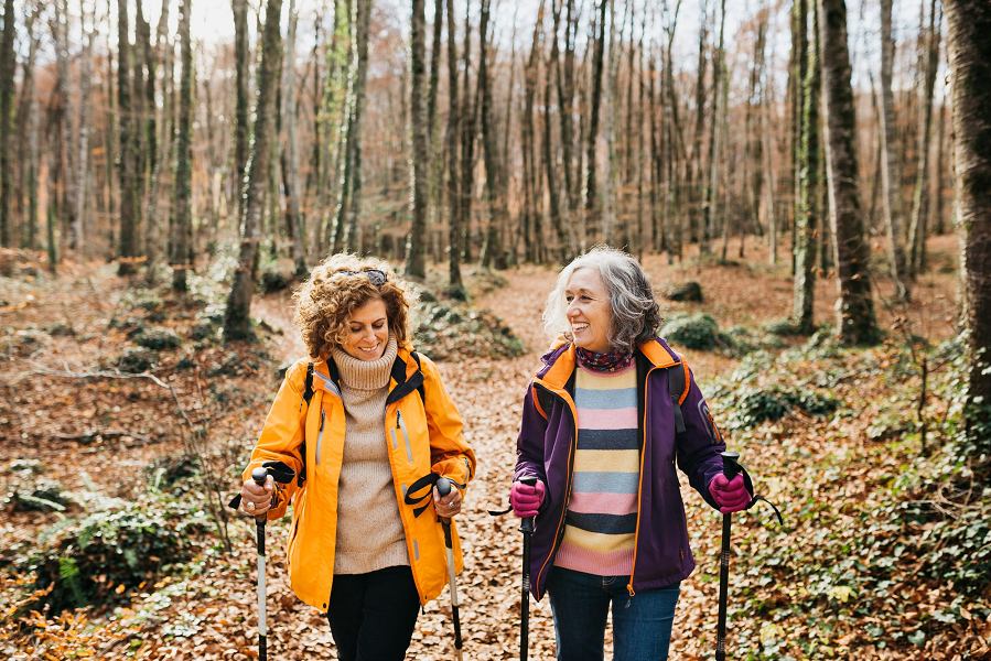 Two women hike through the woods in autumn.
